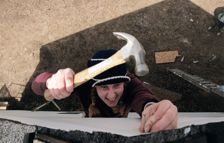 Kiera Knappman nails vinyl siding to the peak of a Habitat for Humanity home during GO Battle Creek.