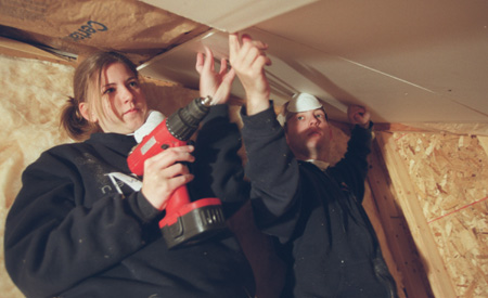 Amy Edge and Sam McMinn hang drywall in the attic of a Battle Creek Habitat for Humanity home.