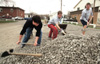 Casey Stafford, Lance Parrott and Chad Farneth spread gravel on the parking lot at University Baptist Church during GO Illinois. - Photo by Justin Veneman