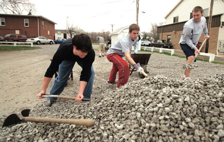 Casey Stafford, Lance Parrott and Chad Farneth spread gravel on the parking lot at University Baptist Church during GO Illinois.