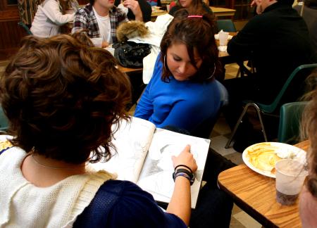 Senior art majors Alanna Taylor and Ellen Kay look through Kelsey Robert's sketchbook at the annual art retreat.