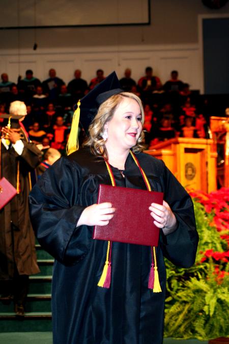 Autumn Brooke Lewis, receiving her bachelor of science in organizational leadership, happily displays her diploma at the fall graduation ceremony.