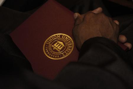 A graduate holds his newly, earned diploma during the fall graduation ceremony.