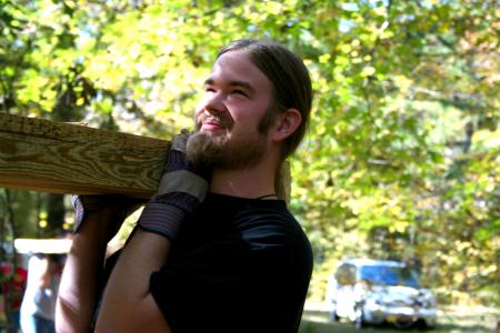 Travis Lutz, sophomore political science major, helps carry a heavy cedar plank to a drop-off point along the walking trail under construction at Pinson Mounds during Day of Remembrance.