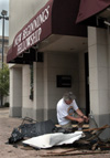 Union theatre professor and New Beginnings Fellowship elder David Burke tries to work loose a chainlink gate which was hurled into the church's exterior wall by the winds of the tornado. - Photo by Jim Veneman