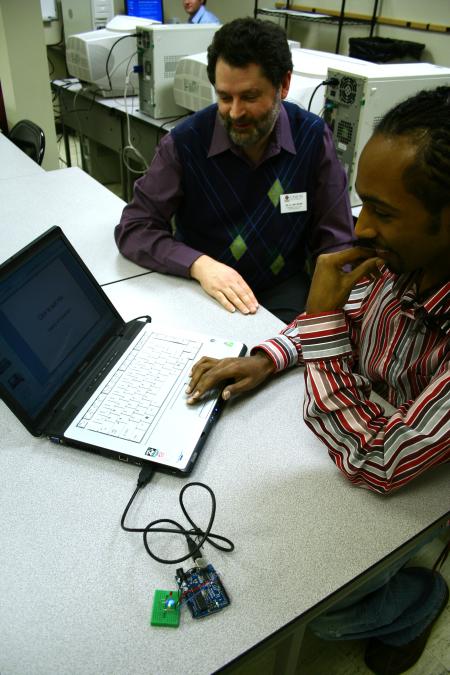 Jan Wilms, chair of the computer science department, oversees a project that Mikias Seid, sophomore computer science major, has put together. 