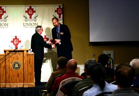 President Dockery presents Micah Watson, conference coordinator, with a gift of appreciation at the start of the Making Men Moral conference.  The conference addressed themes from Robert P. George’s book, Making Men Moral, written 15 years ago.