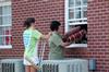 Senior Sara Greenlee and her mother Tina Greenlee strategically move into her room in the Quads through the back window. - Photo by Beth Spain