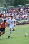 Guilherme Reis, freshman, dribbles the ball away from his Brewton Parker opponent. Watching him is a full crowd of fans enjoying Union's new soccer field stands. - Photo by Kristi McMurry