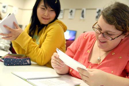 Shinae Giffin, sophomore art major, and Megan March, senior art major, look through design samples from a recent conference during their AIGA meeting. AIGA is a professional association for design. 