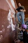 Colby Stinebaugh (top), sophomore art major, and Angela McDaniel, art department secretary, work diligently on a mural for Daddy's Kitchen Table Soup Kitchen on Campus and Community Day. - Photo by Megan Bailey