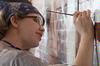 Kelsey Roberts, senior painting major, adds detail to the faces on the mural at Daddy's Kitchen Table Soup Kitchen on Campus and Community Day. - Photo by Megan Bailey
