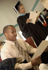 Germantown Education Specialist graduates Michael Lowe (seated) and Debbie Rudzena go over the program for the August 2003 commencement exercises shortly before the ceremony begins. - Photo by Jim Veneman