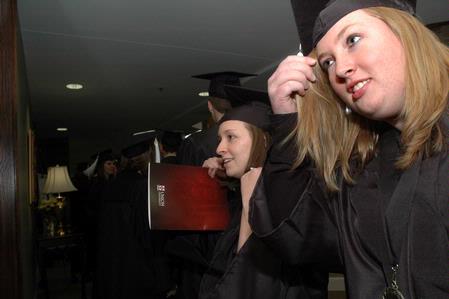 Joanna Sparks, Spanish graduate, and Jessica Vanderpool, ournalism graduate, adjust their caps and hair in the reflection of a glass case before Union's fall graduation ceremonies begin.