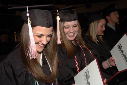 Victoria Green and Kelly Palmer, music education graduates, look over their diplomas during fall graduation.