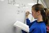 Students in Dr. Troy Rigg's math class write homework problems on the board before class.  - Photo by Morris Abernathy