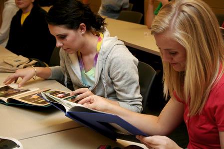 AlLee Browning, sophomore elementary education major, and Sarah Chitwood, junior English and elementary education major, look through photo albums of Angel, Fonsi and Lesley Guilaran's adopted child.