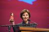 Laura Bush, former first lady of the United States, holds up a bobble head doll of herself while telling a funny story at the 13th annual Scholarship Banquet.  - Photo by Morris Abernathy