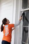 Caitlin Roach, junior history major, scrapes paint and dirt off a window at the recently relocated 1800s home in Casey Jones Village. The history department helped in the restoration of this piece of history, called the Neil House, as a part of Campus and Community Day.  - Photo by Kristi McMurry
