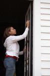 Mary Alisa Techentin, senior history major, cleans a window at the Neil House, an 1800s home that has been relocated to Casey Jones Village. The history department helped in the restoration of this historic home as part of Campus and Community Day.  - Photo by Kristi McMurry