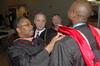 Michael Gray, MBA graduate, along with Dr. Bill Nance, associate dean of McAfee School of Business Administration, help Stacey Miller prepare for the graduation ceremony at West Jackson Baptist Church. - Photo by Beth Spain