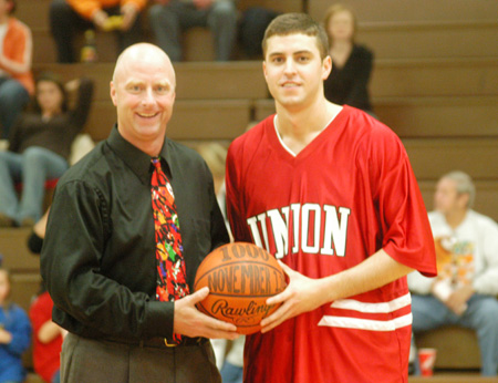 Senior guard Will Harris accepts a game ball from head coach Ralph Turner in recognition of his 1,000th career point with the Bulldogs.