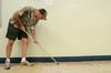Steve Beverly, associate professor of communication arts, scrapes wax from the cafeteria of Lloyd Wood Middle school in preparation of Holt Elementary students. - Photo by Beth Spain