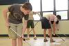Cody Hill, sophomore public relations major, helps other Union students, faculty and staff scrape wax from the Lloyd Wood Middle School cafeteria floor. The school will become the temporary home for Holt elementary, which experienced water damage during the Tuscaloosa tornadoes. - Photo by Beth Spain