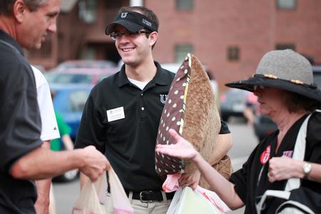 Landon Preston (center), director of donor relations, gathers things from a new student's car during New Student Move-in. 