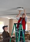 Amanda Chambers and Kate Allen, senior art majors, clean out light fixtures and replace bulbs at Pleasant Plains Baptist Church during Campus and Community Day. - Photo by Jacob Moore