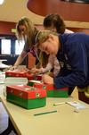 Morgan Roth (front), freshman nursing major, fills out a form for an Operation Christmas Child box during Campus and Community Day. - Photo by Anne Richoux
