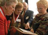 Sue Crocker (’54), Paula Clayton (’54), Fred Cosson (’50), and Christine Fairless (’51) look through the 1954 yearbook during the Class of '54 Reunion Luncheon at Homecoming 2004. - Photo by Jim Veneman