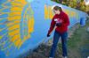 Christa Seyler, freshman nursing major, clears away grass on the football field at North Side high school, in order to re-paint the wall. - Photo by Ebbie Davis