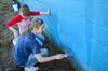 Freshmen nursing majors, Hannah Gerling and Rachel Massey, paint the wall on North Side High School's football field during Campus and Community Day.  - Photo by Ebbie Davis