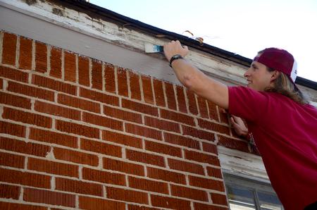 Jake Ryan, senior business administration major, prepares to repaint the trim of a local elderly woman's home during Campus and Community Day.