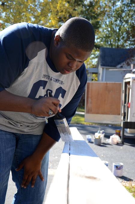 James Barbee, junior elementary education major, paints a railing at a Jackson home during Campus and Community Day.