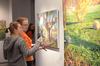 Senior art majors Lori Landon and Rachel Moore discuss one of Lisa D. Line's paintings during an art reception.  - Photo by Anne Richoux