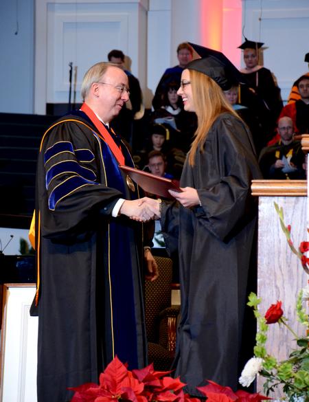 David S. Dockery, president of the university, presents Lindsey Bock, biology graduate, with her diploma at the 2011 Fall Commencement Services.