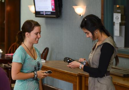 Michelle Lee, sophomore business management major, greets Emily Rich, junior elementary education major, while swiping her identification card for chapel credit.