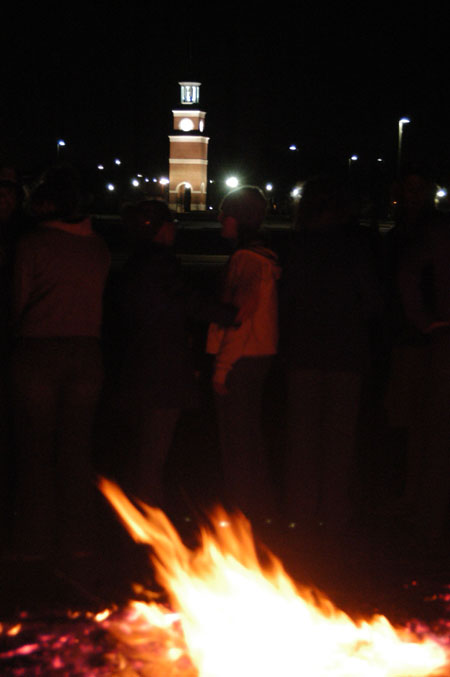 Students warm themselves at the Homecoming bonfire.