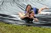Elizabeth Oakes (front), junior public relations major, throws Kappa Delta letters and Becca Orosz, sophomore social work major, throws their family giraffe symbol on the slip 'n slide while celebrating Panhellenic Bid Day. - Photo by Anne Richoux