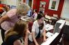 Kayla Oxford, sophomore journalism major, shows a page from the Cardinal & Cream student newspaper to Julia Duin, associate professor of journalism, and Beth Byrd, senior journalism major. - Photo by Jacob Moore