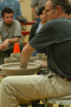 Art students watch closely as artist Chris Staley throws a pot during a ceramics workshop. - Photo by Jonathan Blair