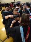 Candace Obadina receives help from fellow master of urban education graduates in getting her robe and hood in place before Spring Graduation. - Photo by Jacob Moore