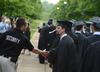 Adam Panisiak, shift supervisor for safety and security, congratulates Mark Waite, Christian studies graduate, during the processional for Spring Graduation.  - Photo by Jacob Moore
