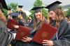 Graduates excitedly open and look at their diplomas during Spring Graduation. - Photo by Anne Richoux