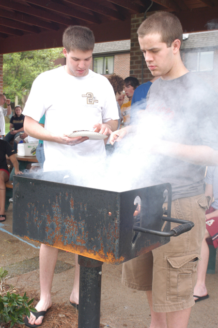 Freshmen Landon Preston and Ryan Hill work the grill at an SGA cookout.