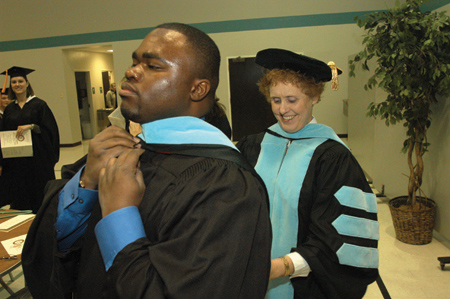 Education professor Carrie Whaley helped M.Ed. graduate Everett Singleton make final adjustments to his graduation robe while waiting for the processional to begin.