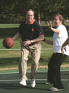President David S. Dockery takes it to the hoop during the dedication of the new Class of 2002 outdoor basketball courts on Sept. 30. Senior Reagan Carfield, psychology major, attempts to stop his progress during the Student vs. Faculty/Staff game. - Photo by Justin Veneman