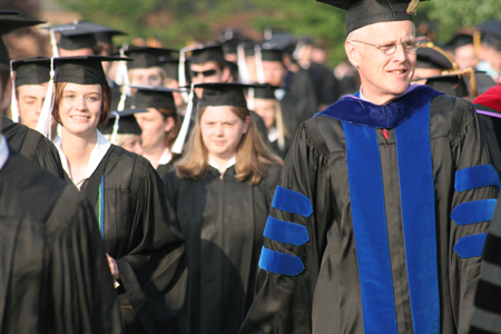 The graduate and faculty processional lines prepare to diverge at spring graduation.
